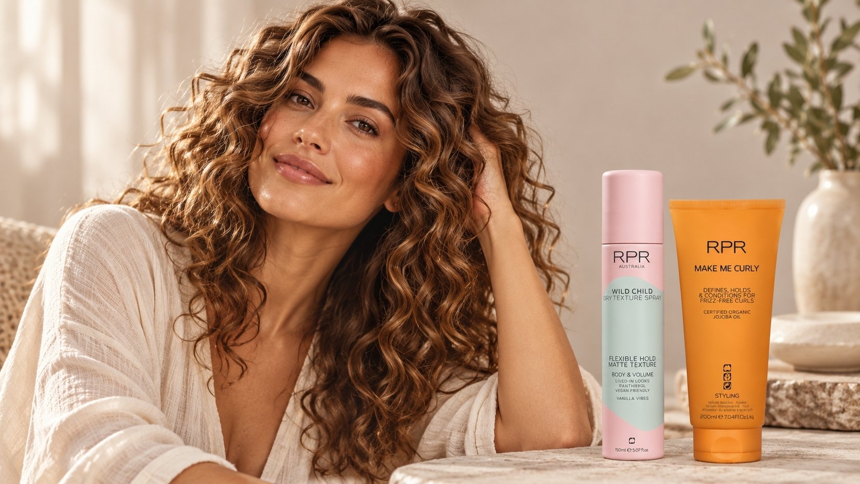 Woman with voluminous brown curls beside RPR Wild Child Dry Texture Spray and Make Me Curly styling cream.